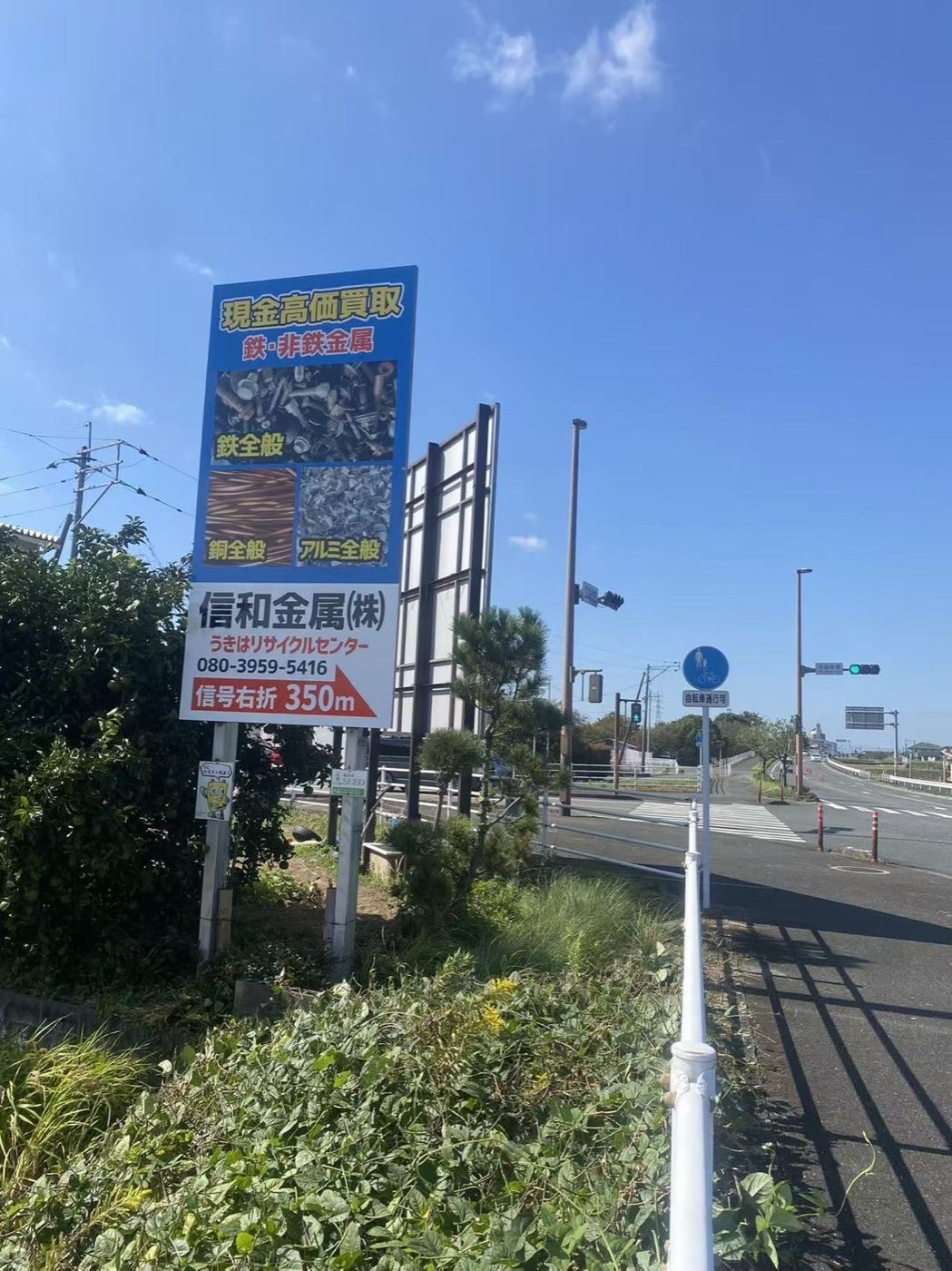 道路脇に立つ信和金属の看板。信号右折350m